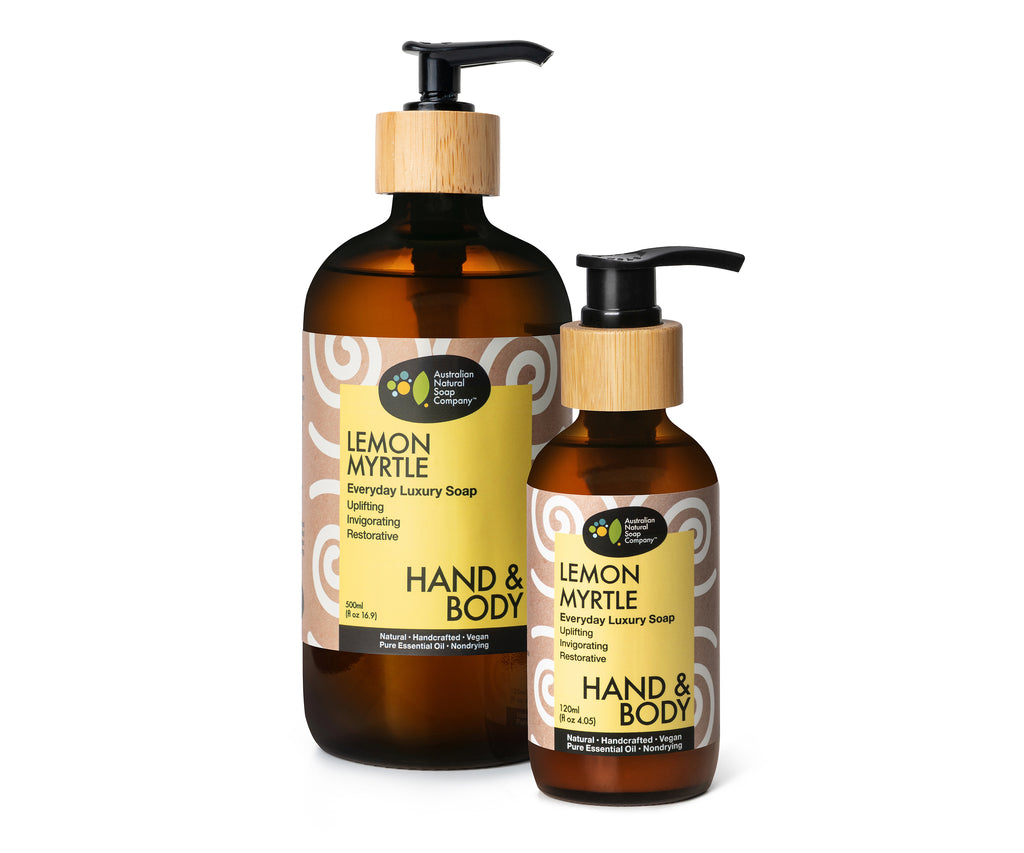 Image of a two glass bottles with a pump top, adorned with a wooden accent around the pump top. The bottle is wrapped with a label featuring a yellow rectangle with a pattern surrounding it. The label prominently displays the text 'Lemon Myrtle' and lists all the uses for the liquid soap